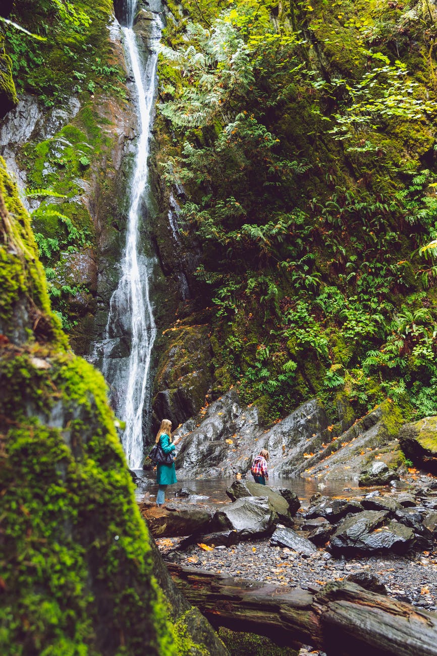 woman standing on rock near waterfall